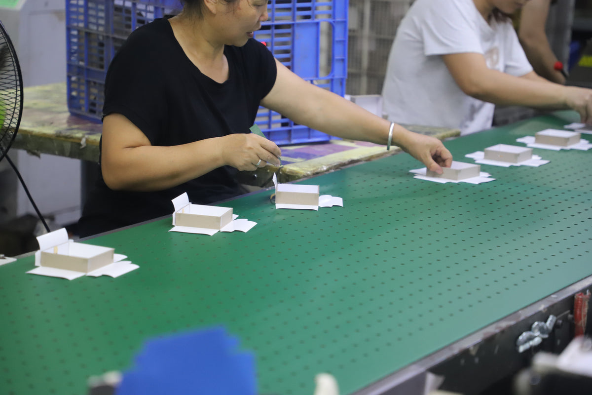 workers assembling custom paper box bases on a packaging production line