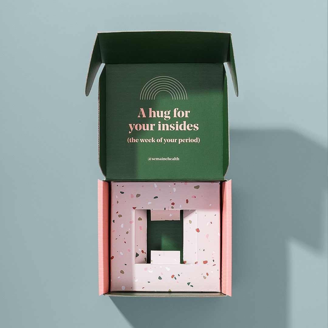 Open custom skincare mailer box with a dark green printed lid, pink insert and product-fit opening.