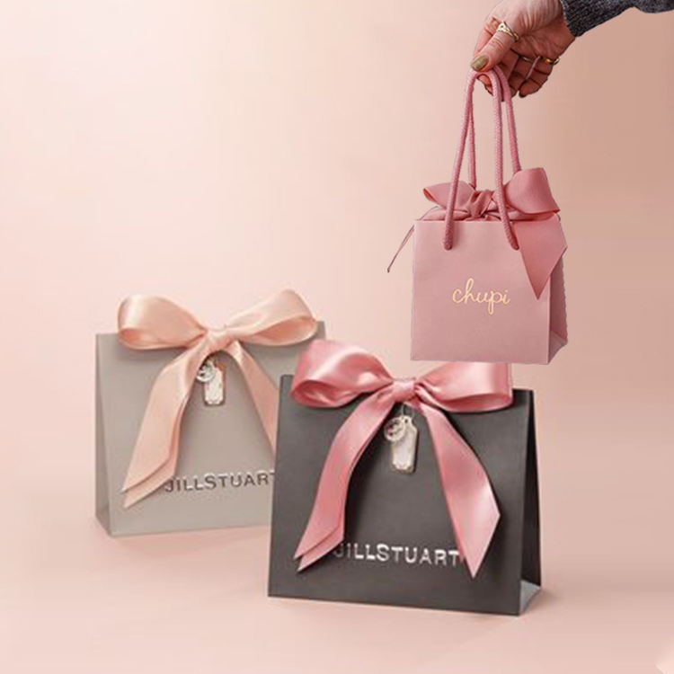 Pink, gray and black custom paper gift bags with ribbon bows and cord handles.