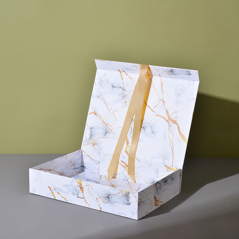 Open white marble-print folding gift box with gold veining and ribbon accents.