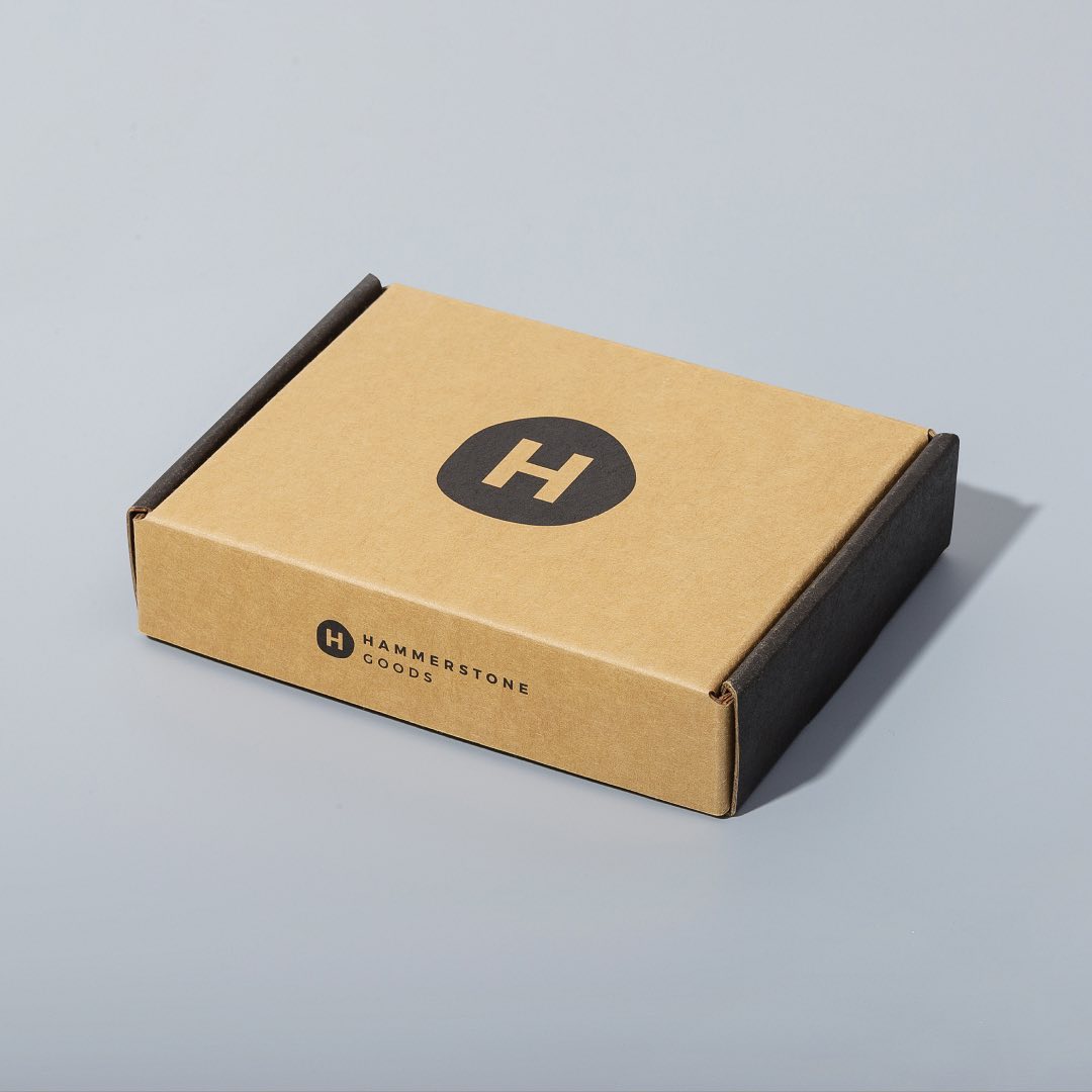 Closed kraft corrugated mailer box with a flat tuck-in lid and a black printed logo.